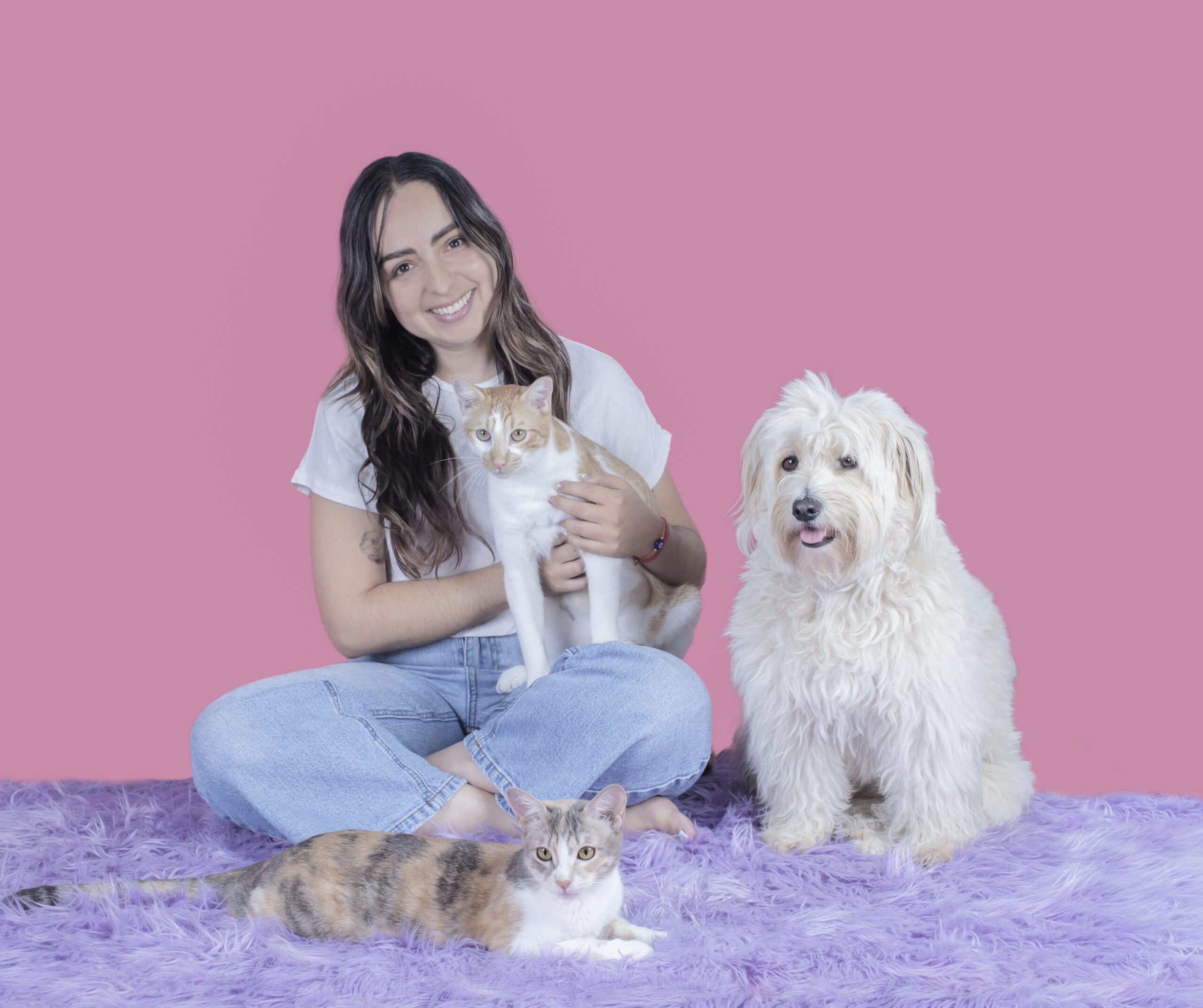 young woman with dark brown hair, siting with a flufy dog, a ginger cat and a pastel calico cat.